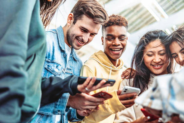 istock Diverse group of young people using smart mobile phone device outside - University students watching cellphone in college campus - Happy teenagers addicted to social media - Technology concept 1474990578