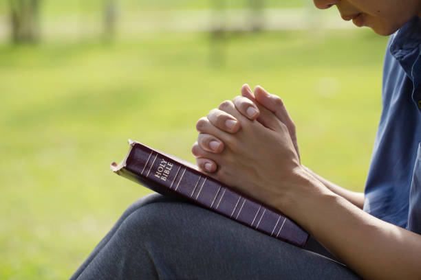 menschenhände beten morgens bei schönem sonnenlicht über einer bibel auf einem feld. hände gefaltet, um zu beten und den segen gottes zu suchen, bibelkonzept für glauben, spiritualität, anbetung und religion - fasten stock-fotos und bilder