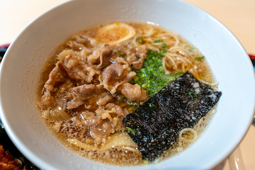Hot bowl of Ramen noodles with egg, beef seaweed, green onions and taro chips. Ramen noodles in a miso soup broth. Healthy Japanese lunch at a restaurant. Bowl of noodle soup.
