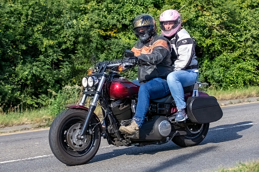 Potterspury,Northants, UK - August 14th 2022. Man and woman on a 2015 1690 cc HARLEY DAVIDSON motorcycle travelling on an English country road