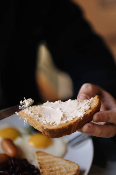 istock Man spreads butter on tested bread during breakfast in restaurant on terrace 1474996221