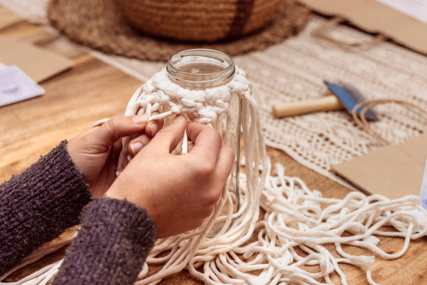 istock White macrame. Young girl fixes the macrame knots so that they do not unravel. 1475001829