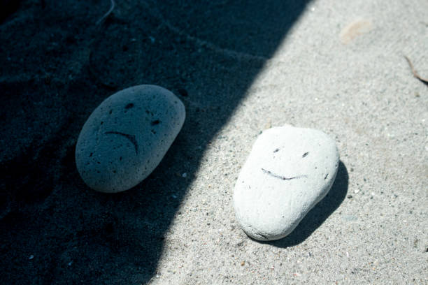 smiling and sad carving on two small white stones on the sand