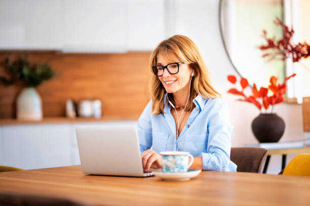 istock Attractive woman with earphones using laptop for work 1475003343