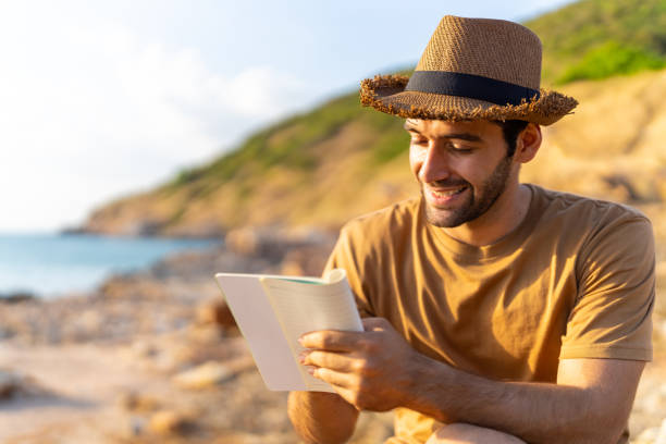 istock Caucasian man writing journey memories during sitting on coastline hill. 1475004411