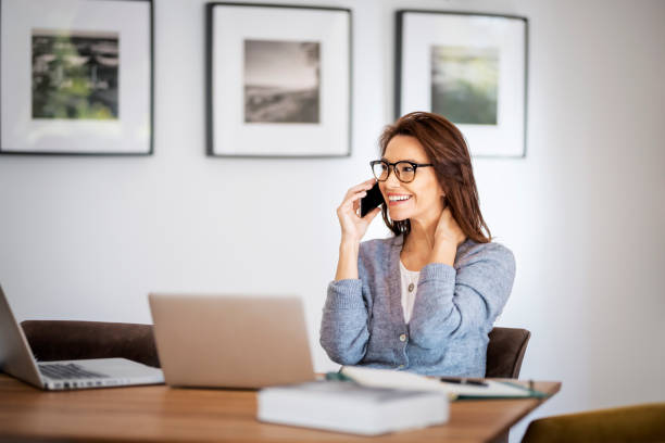 istock Attractive middle aged woman wearing casual clothes and using cellphone and laptops for work 1475004426
