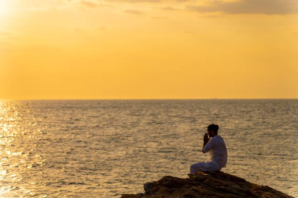 istock Caucasian man practicing meditation with ocean on coastal hill at summer sunset. 1475004476