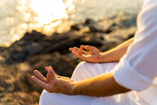 istock Caucasian man practicing meditation with ocean on coastal hill at summer sunset. 1475004477