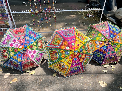 Three colourful, embroidered, mass produced sun umbrellas for sale in a Cochin market