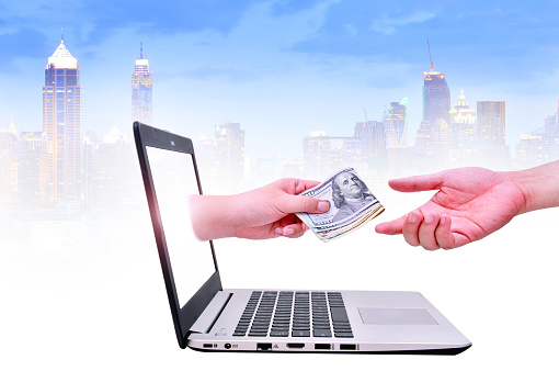 Get money from online business holding US dollar in hand. business concept on urban background.
