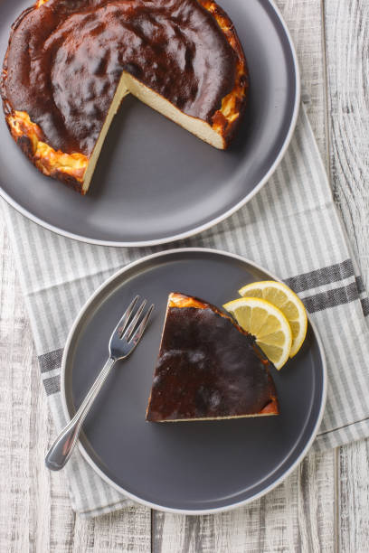 istock Sliced tender creamy burnt basque cheesecake with lemon wedges close-up on a plate. Vertical top view 1475005686