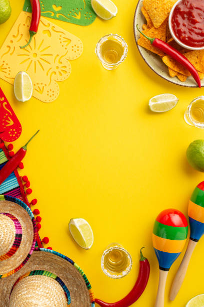 istock Cinco-de-mayo concept. Top view vertical photo of tequila nacho chips salsa sauce chilli lime sombrero striped serape garland maracas on isolated bright yellow background with copyspace in the middle 1475006955