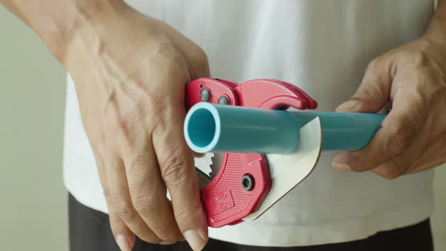 Plumber Cutting PVC Pipe with an cutter water pipe