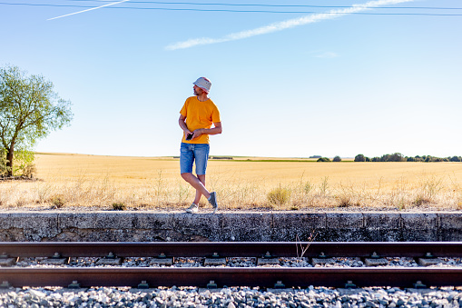 Spain. Castilla la Mancha. Man in summer outfit and hat waiting for train at rural halt