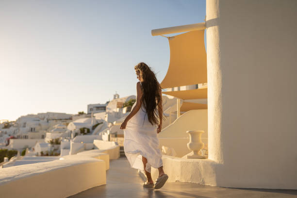 giovane donna asiatica femminile con vestito bianco in una vacanza a santorini, godendo della vista dell'architettura tradizionale - long long hair dress young adult foto e immagini stock