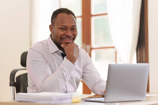 istock Smiling American African makes financial report and studies annual figures, analyzes profits. Accountant checks status of financial 1475013295