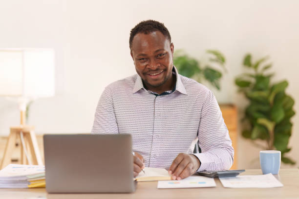 istock Smiling American African makes financial report and studies annual figures, analyzes profits. Accountant checks status of financial 1475013301