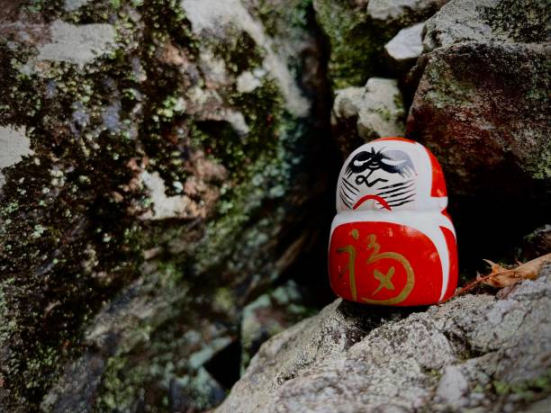 だるままたは石の上に立つ伝統的な日本人形