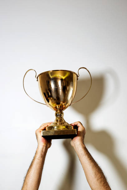 istock Golden winners cup in man's hands on white background isolated, copy space, space for text 1475016737