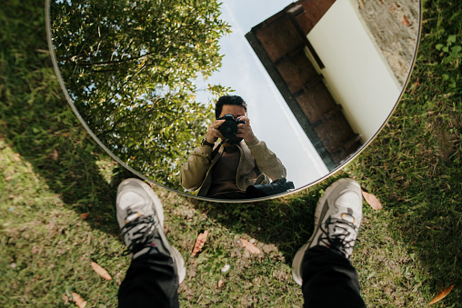 A creative portrait of a photographer, reflected on a mirror placed on the ground
