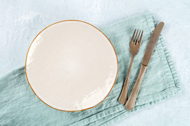 istock An empty white plate with a gold rim, with a fork and a knife 1475018854