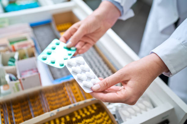 Female pharmacist holding medicines Pharmacists holding pills in hands above drawer with medicines. Close up of hands, unrecognizable person. drugs stock pictures, royalty-free photos & images