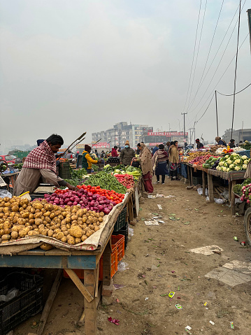 Delhi, India - January 09, 2023 : Stock photo showing setting up of produce market with fruit and vegetables being sold by market traders from outdoor stall displays. Produce can be seen on temporary trolley cart stalls.