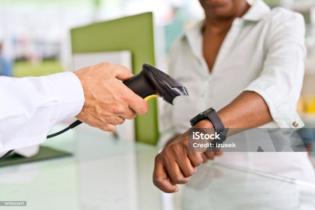Smart watch mobile payment Smart watch mobile payment in pharmacy. Pharmacist holding bar code reader to the smart watch on female hand. Close up of hands, unrecognizable person. Paying Stock Photo