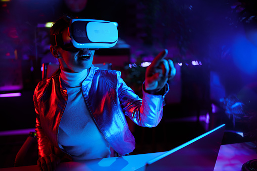 Neon metaverse futuristic concept. excited modern business woman in vr headset in modern office working in metaverse.