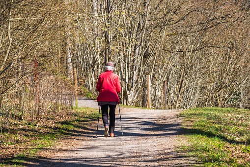 Falköping, Sweden-April, 2020: Senior woman walking on a path in the spring sun