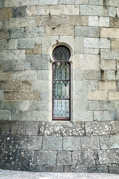Gelendzhik, Russia - August 12 2021: Old medieval window surrounded by stone wall in castle attracts tourists attention. Historical exterior illuminated by bright sunlight