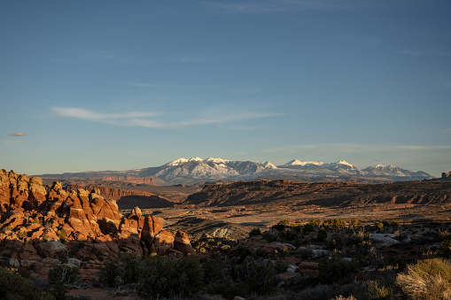 Sun Begins To Set Over The Fiery Furnace With The Snowy La Sal Mountains In The Distance in Arches National Park