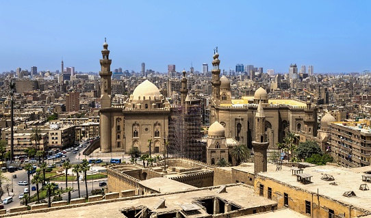 Cairo, Egypt, April 16, 2022: View of the Mosque-Madrasa of Sultan Hassan (left) and the Al-Rifa'i Mosque (right) in Islamic Cairo. In the middle there is the small Al-Mahmodyah Mosque whose minaret is being repaired.