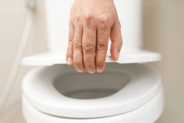 close up hand of a woman closing the lid of a toilet seat. hygiene and health care concept. - toilet public restroom bathroom flushing imagens e fotografias de stock