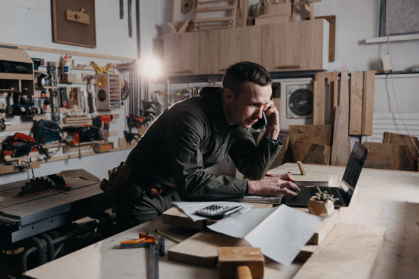 istock Carpenter master is phoning with the smartphone in his carpentry workshop 1475038732