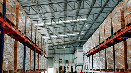 Rows of shelves partially filled with boxes of manufactured goods in a trading company's warehouse.