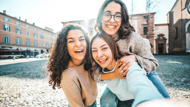 Three young women taking selfie picture with smart mobile phone outside - Girlfriends having fun on a sunny day out in city street - Life style concept with delightful females smiling at camera Three young women taking selfie picture with smart mobile phone outside - Girlfriends having fun on a sunny day out in city street - Life style concept with delightful females smiling at camera delightful stock pictures, royalty-free photos & images