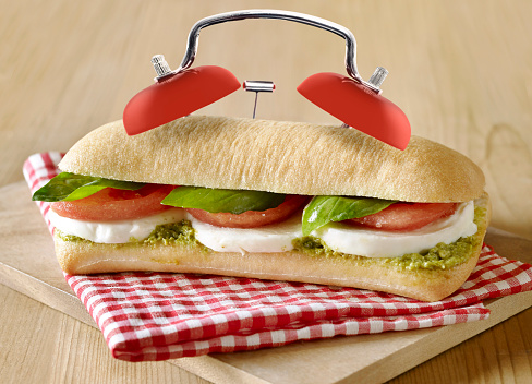 Delicious fresh vegetarian sandwich with alarm clock ringer on wooden table