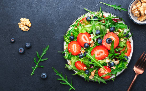 istock Strawberry and herbs healthy salad with arugula, blueberries and walnuts, black kitchen table, place for text. Fresh useful vegan dish for healthy eating 1475044002