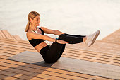 Athletic Middle Aged Woman Making V-Up Abs Workout Outdoors