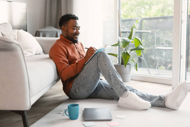 istock Happy African American Guy Writing Taking Notes Sitting At Home 1475047807