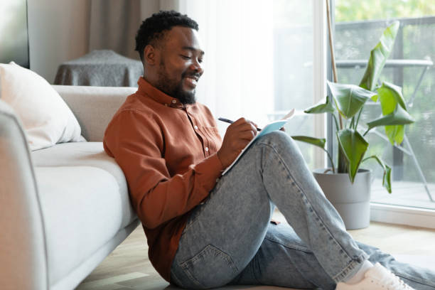 istock Cheerful Black Male Writing Taking Notes Sitting At Home 1475047818