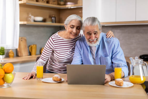 istock Smiling Elderly Spouses Relaxing With Laptop While Having Breakfast In Kitchen 1475048886