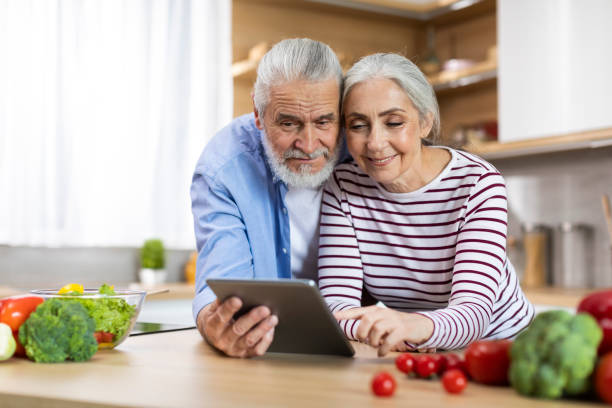 istock Portrait Of Happy Elderly Spouses Using Digital Tablet In Kitchen Interior, 1475048896