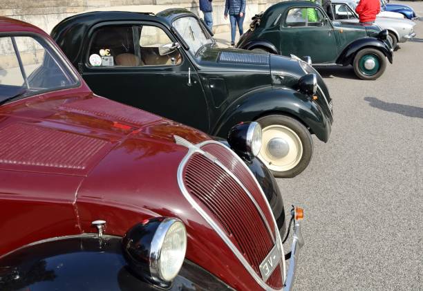 Three vintage Fiat Topolino cars at the roadside Percoto, Italy. March 19, 2023. Three Fiat 500 Topolino, vintage car from the Thirties, waiting to participate to a collector's car auto gathering later. fiat 500 topolino stock pictures, royalty-free photos & images