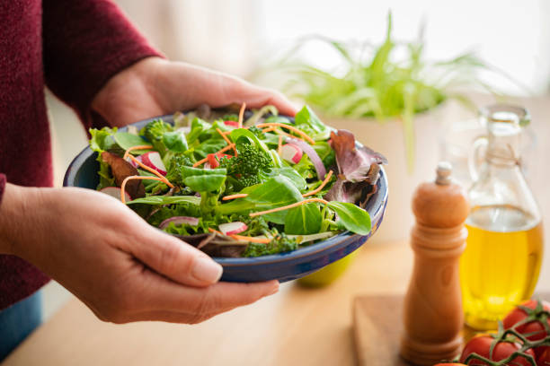 istock Woman serving fresh salad plate on table 1475052991