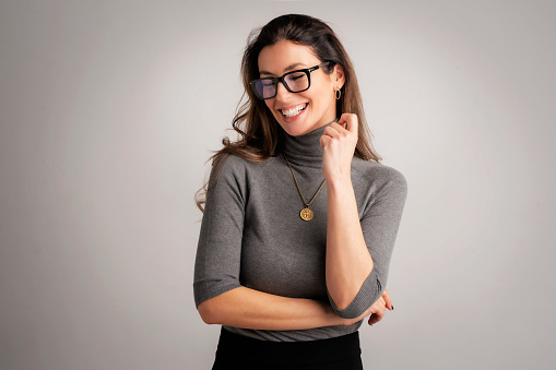Close-up of an attractive mid aged woman cheerful smiling . Brunette haired female wearing eyewear and standing at isolated background. Copy space.