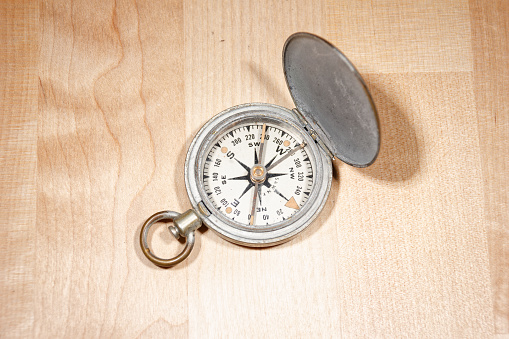 Open old vintage compass on wooden table