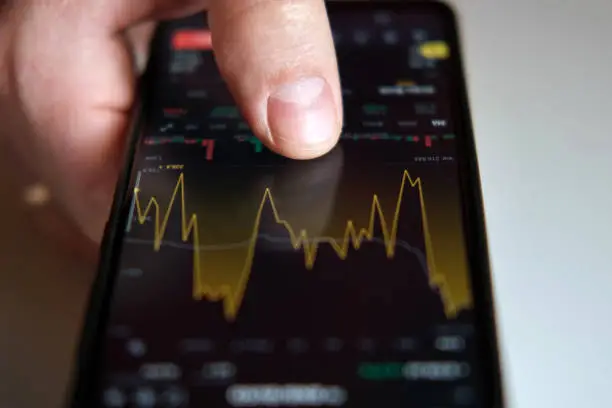 Photo of Businessman trader using smartphone checking stock exchange. Man using mobile phone with investing application. Stock market investment and trading cryptocurrency on app in hand. Online business data