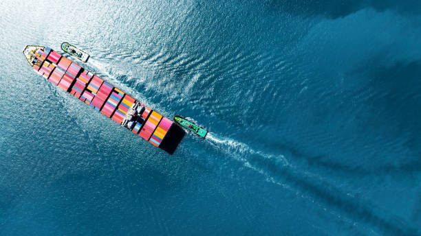 istock top view Cargo Container Ship with Tug boat carrying container and running very fast for export import cargo from container yard port to custom ,Contrail line in the ocean 1475055816